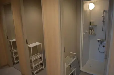 a bathroom with a shower and a toilet and a door at Tokyo Central Youth Hostel in Tokyo