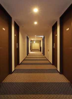 a corridor of a hotel with a long hallway at Keio Presso Inn Tokyo Kudanshita in Tokyo