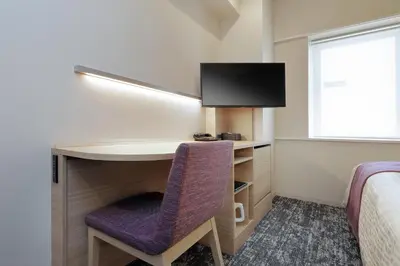 a room with a desk and a tv and a bed at Keio Presso Inn Tokyo Kudanshita in Tokyo