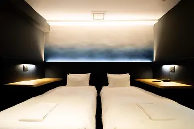 two beds in a small room with two lamps at Hotel New Shohei in Tokyo