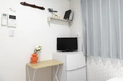 a room with a television on a white refrigerator at nestay inn tokyo senju in Tokyo