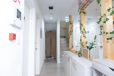 a hallway with white walls and a staircase with plants at nestay inn tokyo senju in Tokyo