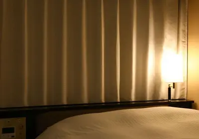 a bedroom with a bed and a lamp next to a window at APA Hotel Tokyo Kiba in Tokyo