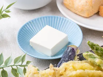 a blue plate with a piece of cheese and asparagus at APA Hotel Asakusa Kuramae in Tokyo