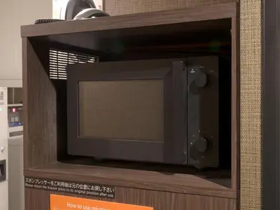 a microwave oven sitting on top of a wooden cabinet at APA Hotel Nihonbashi Hamacho Ekiminami in Tokyo