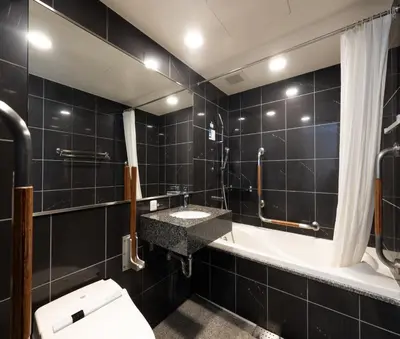 a black tiled bathroom with a sink and a tub at APA Hotel Nihonbashi Hamacho Ekiminami in Tokyo