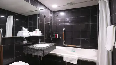 a black tiled bathroom with a sink and a tub at APA Hotel Tsukiji Ekiminami in Tokyo