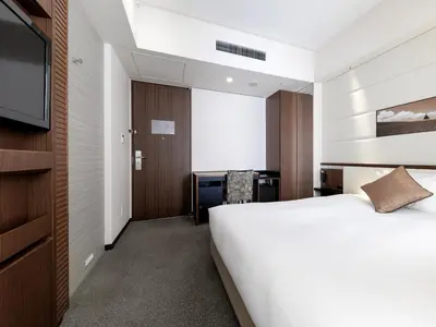 a hotel room with a bed and a flat screen tv at Solaria Nishitetsu Hotel Ginza in Tokyo