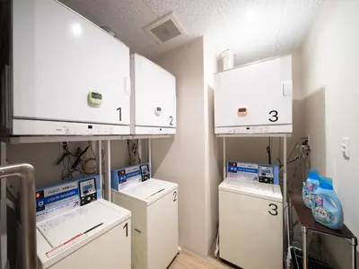 a laundry room with three machines and white cabinets at Super Hotel Tokyo Shiba in Tokyo
