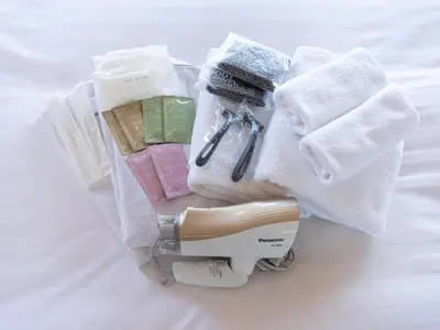 a hair dryer sitting on a bed with towels at Tabist Urban Stays Asakusa in Tokyo