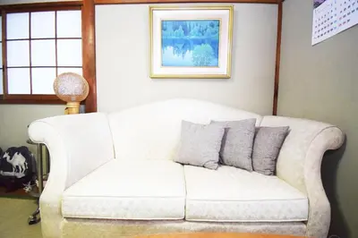 a white couch in a living room with a picture at Oasis Minamiyukigaya in Tokyo