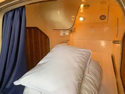 a white pillow in a small room with a window at Capsule Inn Kinshicho in Tokyo