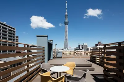 a balcony with tables and chairs and a view of the tv tower at Playsis East Tokyo in Tokyo