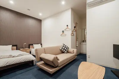 a bedroom with a couch and a bed and a tv at Playsis East Tokyo in Tokyo