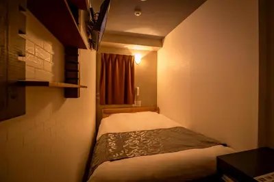 a small bed in a small room with a window at Hotel Peace (Adult Only) in Tokyo