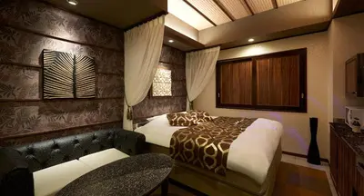 a bedroom with a bed and a chair and a couch at HOTEL EXE (Adult Only) in Tokyo