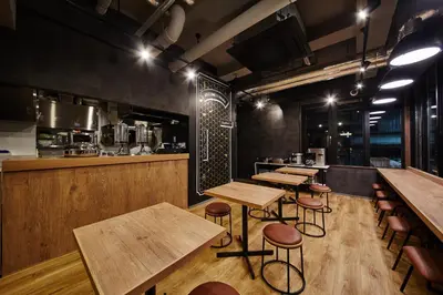 a restaurant with wooden tables and stools and a kitchen at HOTEL AMANEK Asakusa Ekimae in Tokyo
