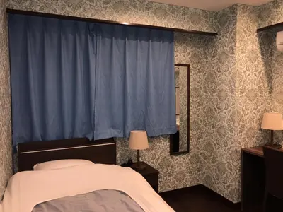 a bedroom with a bed and a blue curtain at Hatoya Hotel in Tokyo