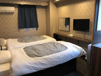a hotel room with a bed and a flat screen tv at Hatoya Hotel in Tokyo