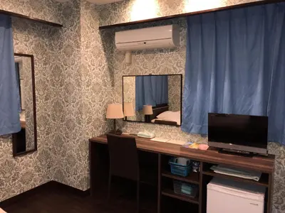 a bedroom with a desk with a television and a mirror at Hatoya Hotel in Tokyo