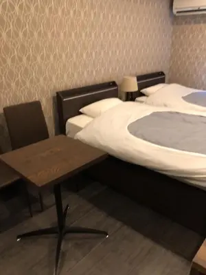 a bedroom with two beds and a table and a table at Hatoya Hotel in Tokyo