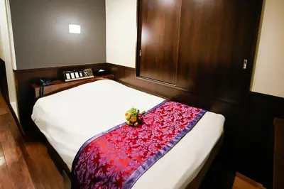 a bedroom with a bed with a red blanket at Ikebukuro Central Hotel in Tokyo