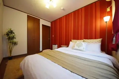 a bedroom with a large white bed with red walls at The Nest Ikebukuro House in Tokyo