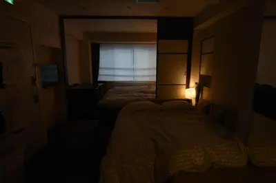 a dark bedroom with two beds and a window at KandoStay EAST TORANOMON in Tokyo