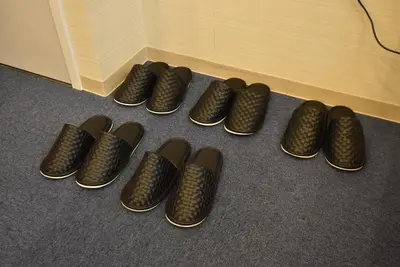 a row of black shoes sitting next to a wall at KandoStay EAST TORANOMON in Tokyo