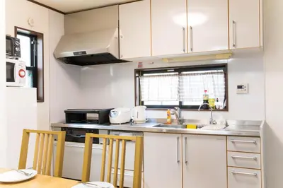 a kitchen with white cabinets and a table and chairs at Tokyo Aoto House in Tokyo
