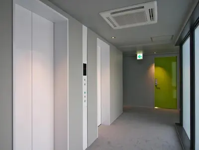 a hallway with white walls and a green door at Shibuya Granbell Hotel in Tokyo