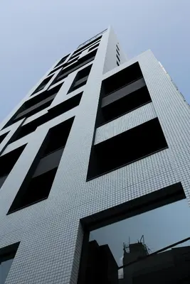 a tall white building with black windows at Shibuya Granbell Hotel in Tokyo