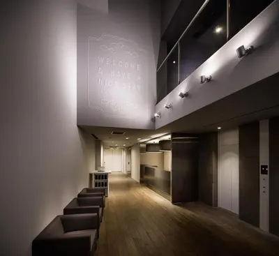 a long hallway with a waiting room with stools at Shibuya Granbell Hotel in Tokyo