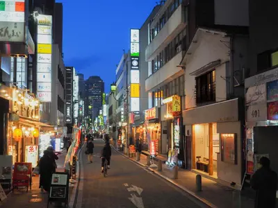 a city street at night with people riding bikes at TOKYO LITTLE HOUSE in Tokyo