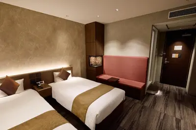 a hotel room with two beds and a chair at Ginza International Hotel in Tokyo