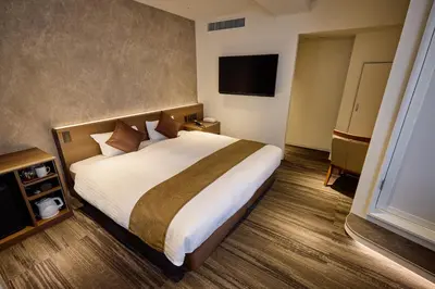 a hotel room with a bed and a flat screen tv at Ginza International Hotel in Tokyo