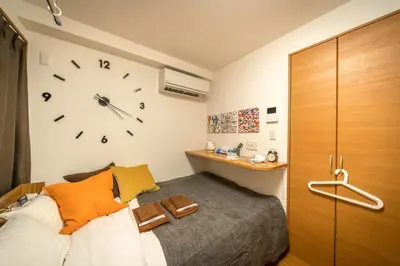 a bedroom with a bed and a clock on the wall at Maison de Takinogawa in Tokyo