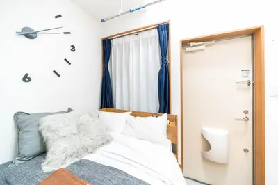 a bedroom with a bed and a clock on the wall at Maison de Takinogawa in Tokyo