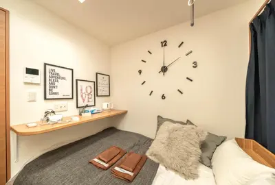 a bedroom with a bed and a clock on the wall at Maison de Takinogawa in Tokyo