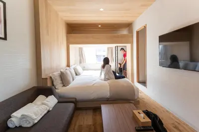a woman sitting on a bed in a room at Sakura Cross Hotel Shinjuku East in Tokyo