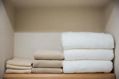 a pile of towels are stacked on a shelf at KAGO 34 Tokyo by Shukuba HOTEL in Tokyo