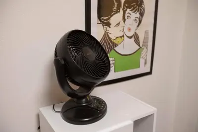 a black fan sitting on top of a white shelf at Papa101 in Tokyo