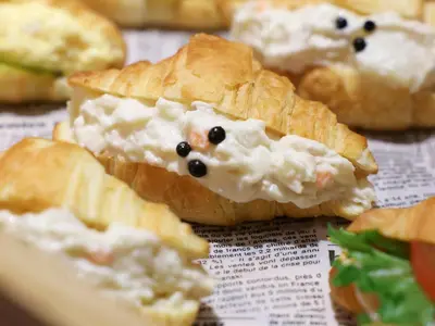 a close up of a sandwich with cheese and black olives at Dormy Inn Premium Shibuya-jingumae in Tokyo