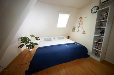 a bedroom with a large bed and a woman jumping on the wall at SHINJUKU 5-ROOM Family house in Tokyo
