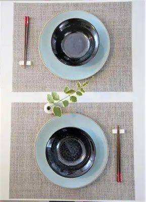 a black plate sitting on top of a table with chopsticks at SHINJUKU 5-ROOM Family house in Tokyo
