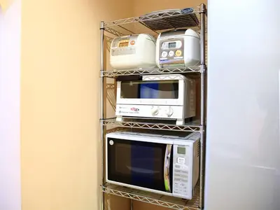 three microwaves and appliances on a shelf in a room at COZY INN Tokyo Sakura Town in Tokyo