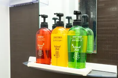 four different colored bottles sitting on a shelf at Guest House One More Heart at TSUKIJI 1 in Tokyo