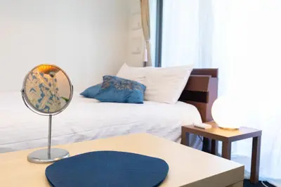 a room with a bed and a table with a mirror at Guest House One More Heart at TSUKIJI 1 in Tokyo