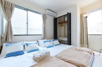 a bedroom with a large white bed with blue pillows at H-Nishikamata ColorBee House in Tokyo