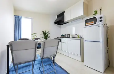 a kitchen with a white refrigerator and two chairs at H-Nishikamata ColorBee House in Tokyo